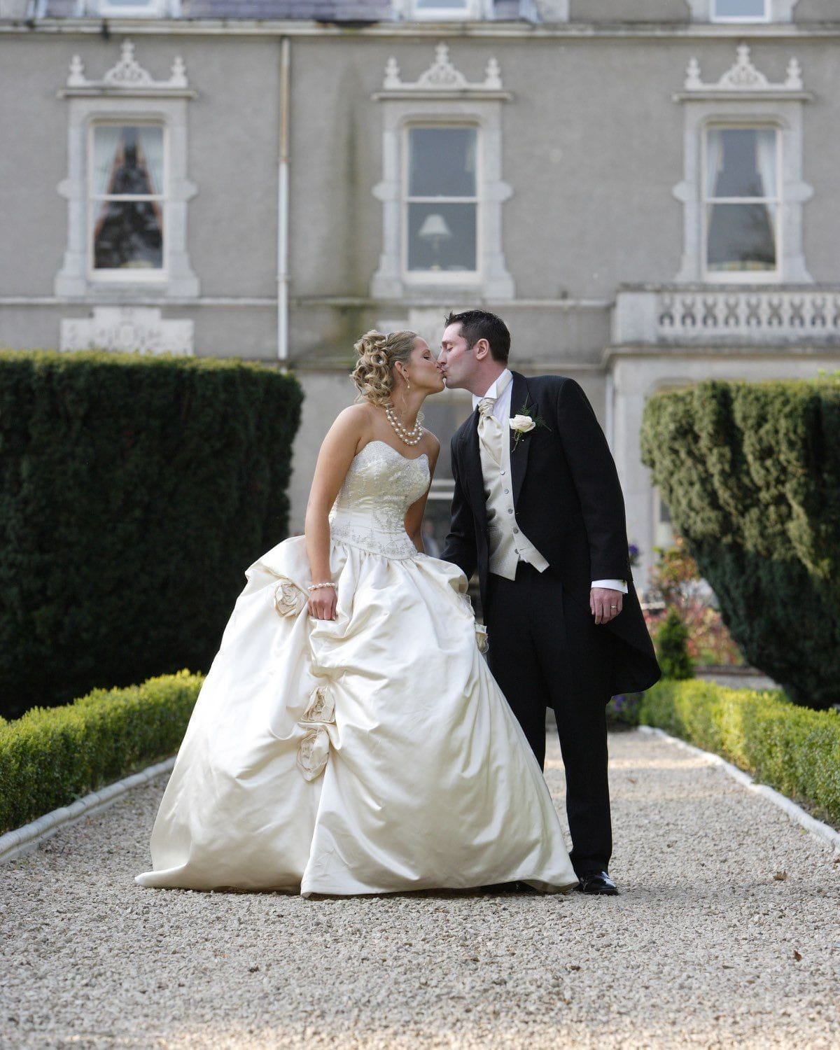 The bride and groom have a kiss in the beautiful gardens behind the Killashee House Hotel in Naas, Co Kildare