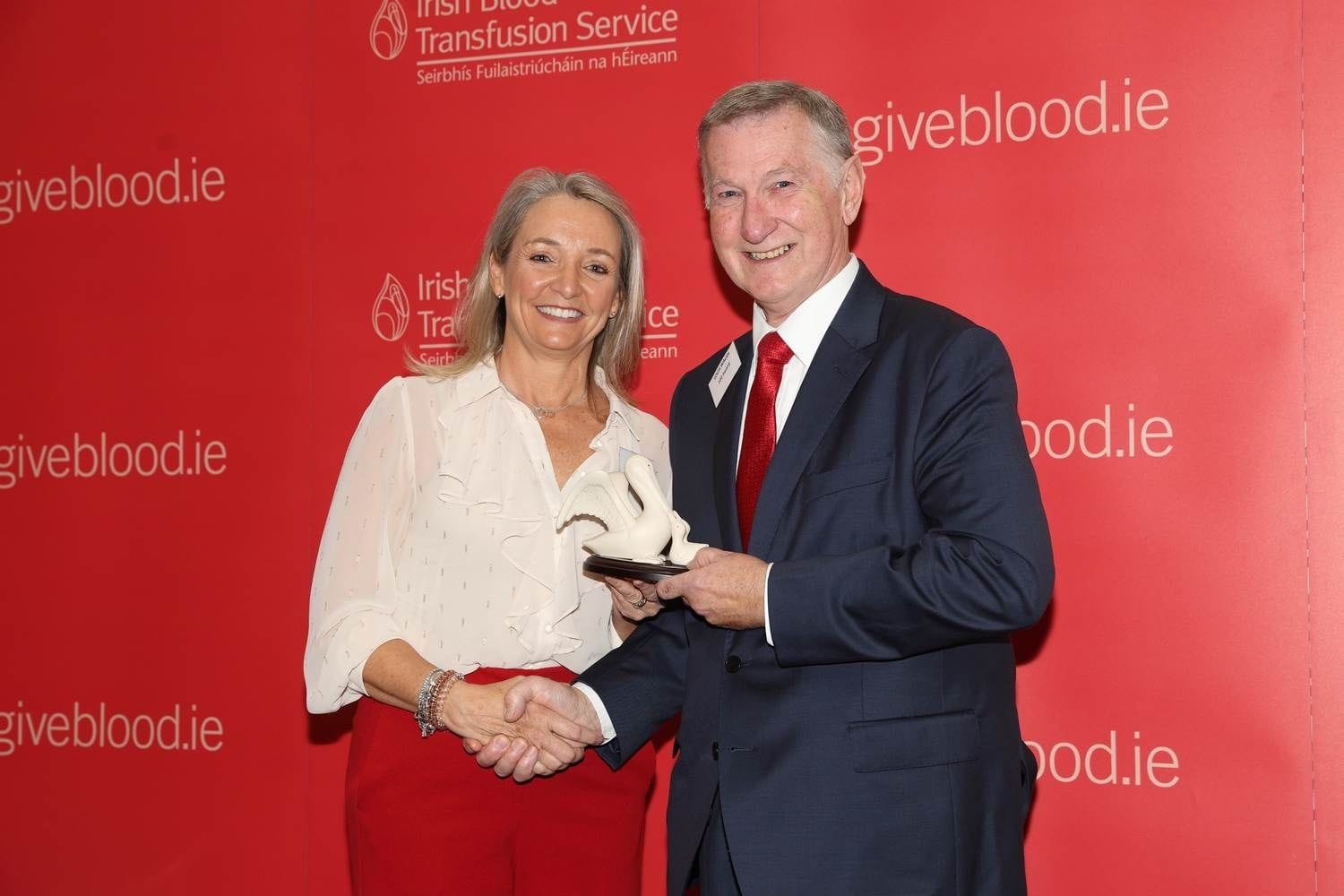 A donor accepting his one hundred  time donation award of a porcelain pelican. The one hundred time award can be for blood or platelets