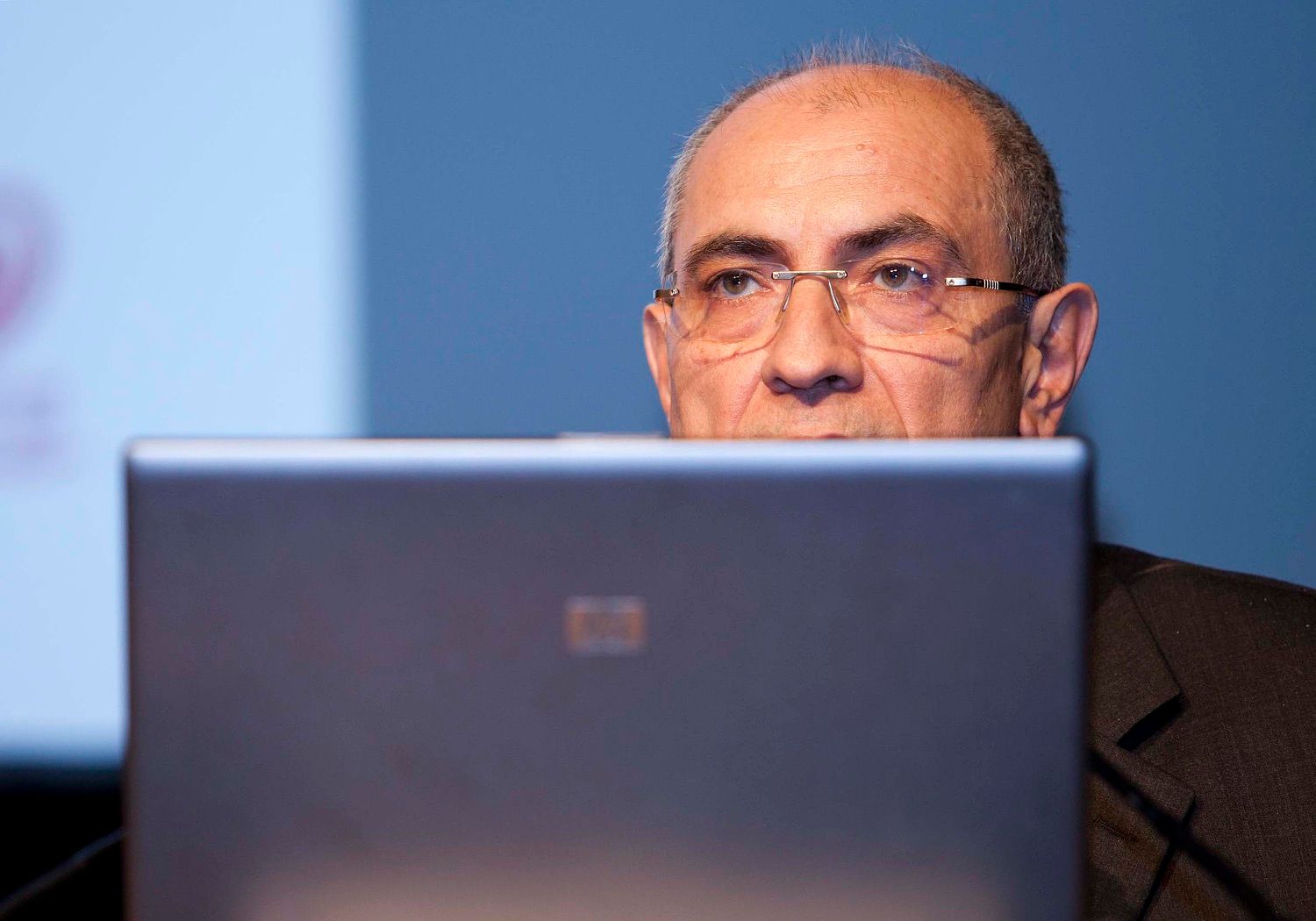 A speaker glances over the top of his laptop at a conference