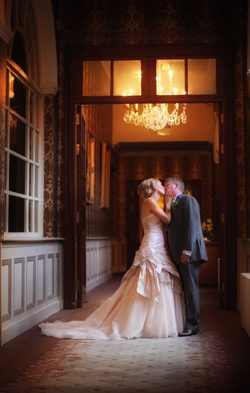 Light floods through a window onto the bride and groom having a quiet kiss, at the Killashee Hotel, Naas, Co Kildare