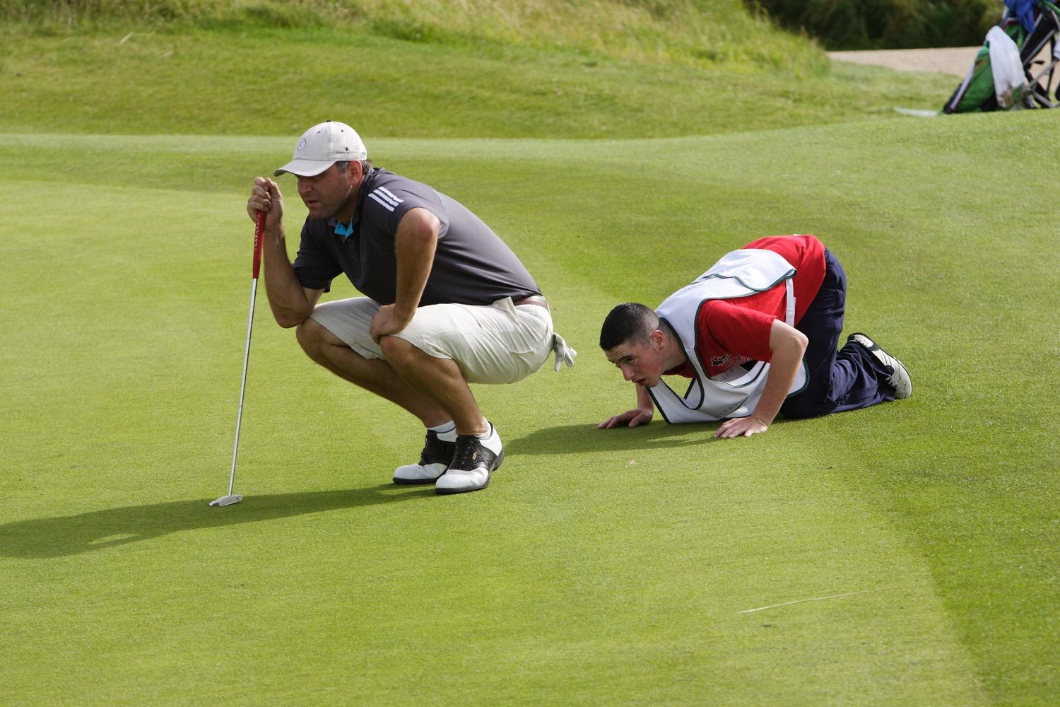 The caddie double checks the lie of the green so he can give the player the best advice87