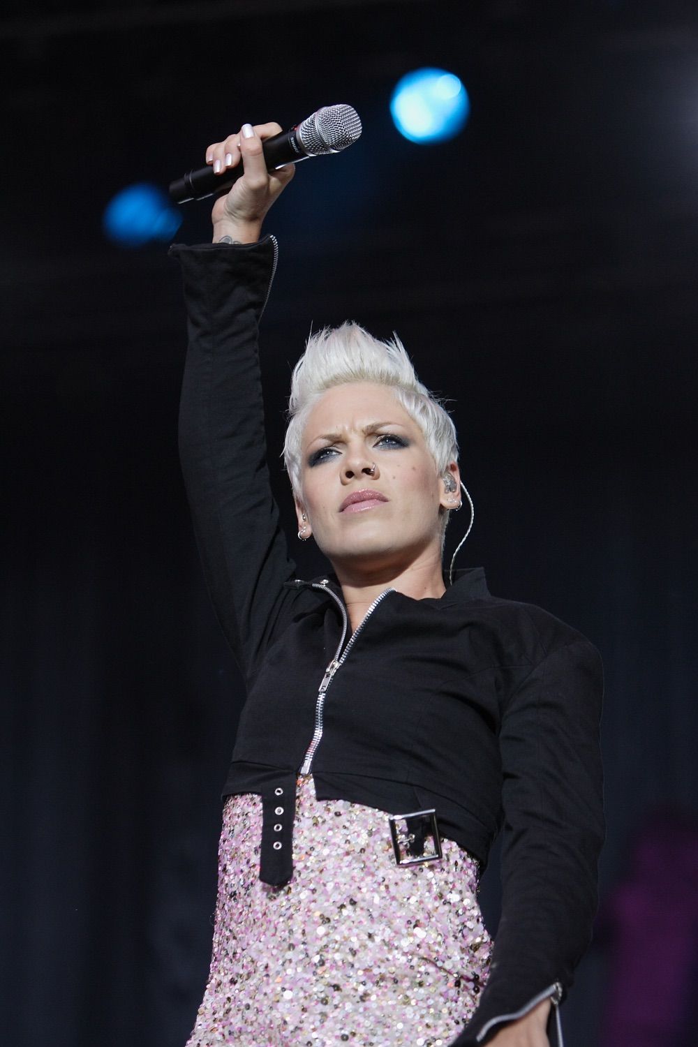 Pink onstage holding her microphone up over her head