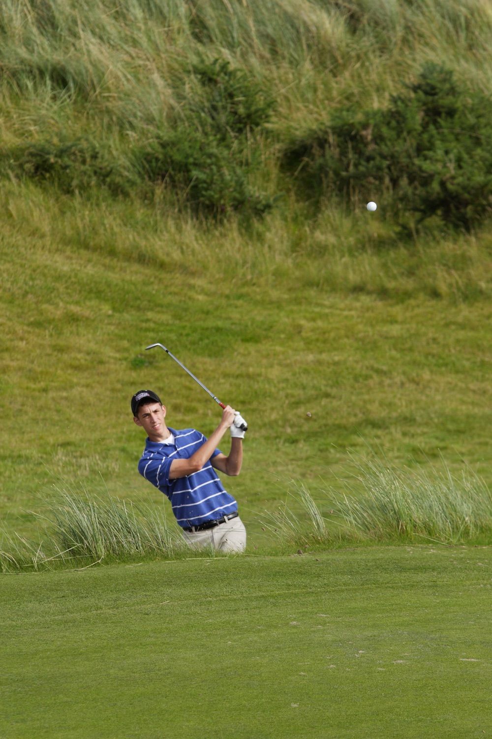 A young player takes a nice shot out of a bunker and up onto the green