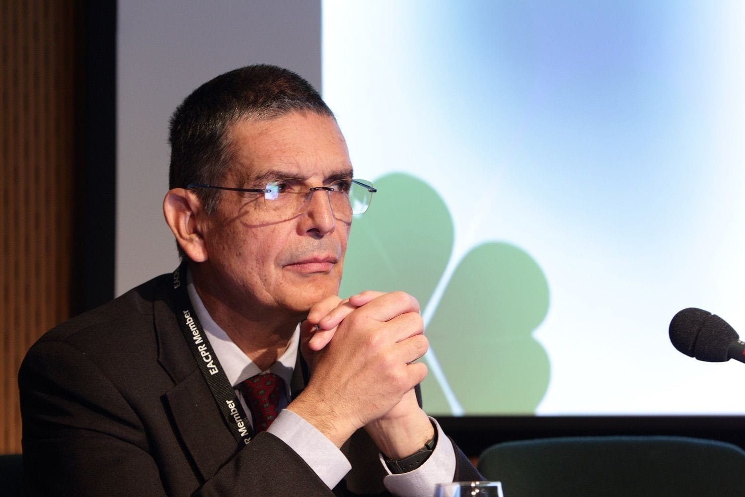 One of the speakers leans forward on his elbows and holds his hands up to his chin during a conference in the Dublin Convention Centte