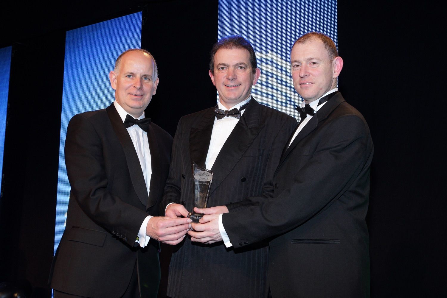 A photograph of two of the recipients accepting his award from a Deloitte representative