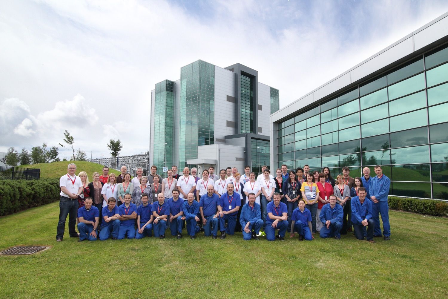 Staff at a company stand out side their building for a group photograp on a lovely bright day