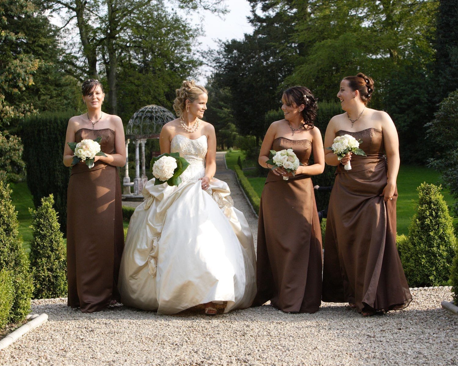 The bride and her three bridesmaids walk along the garden path behind the Killashhe House Hotel