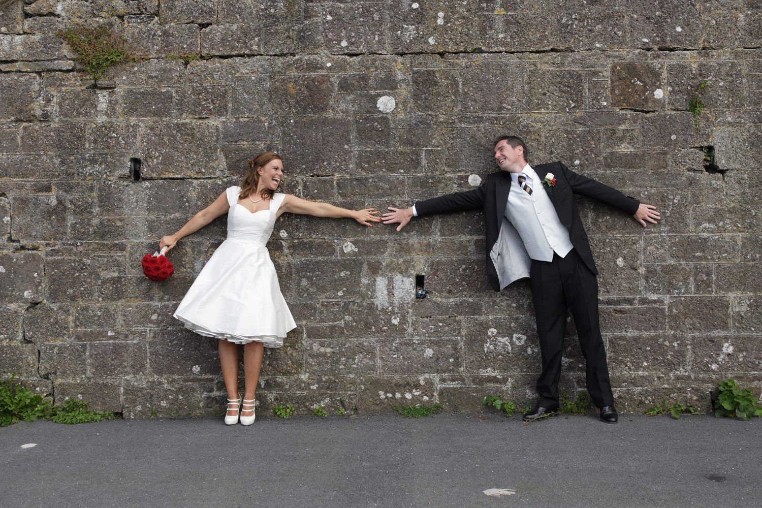 The bride and groom have a fun shot against the wall at Duncannon, Co Wexrofd