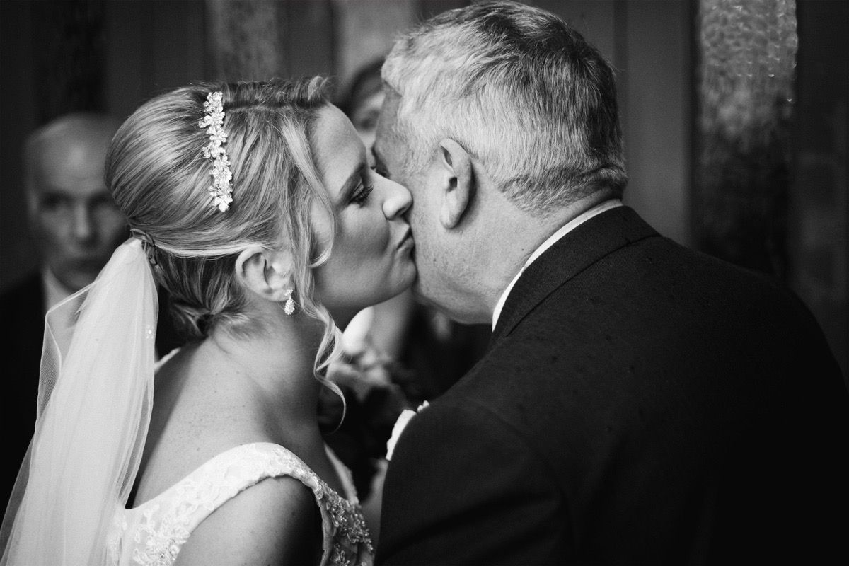 The bridge gives her father one last kiss on the cheek at the top of the aisle before he gives her away