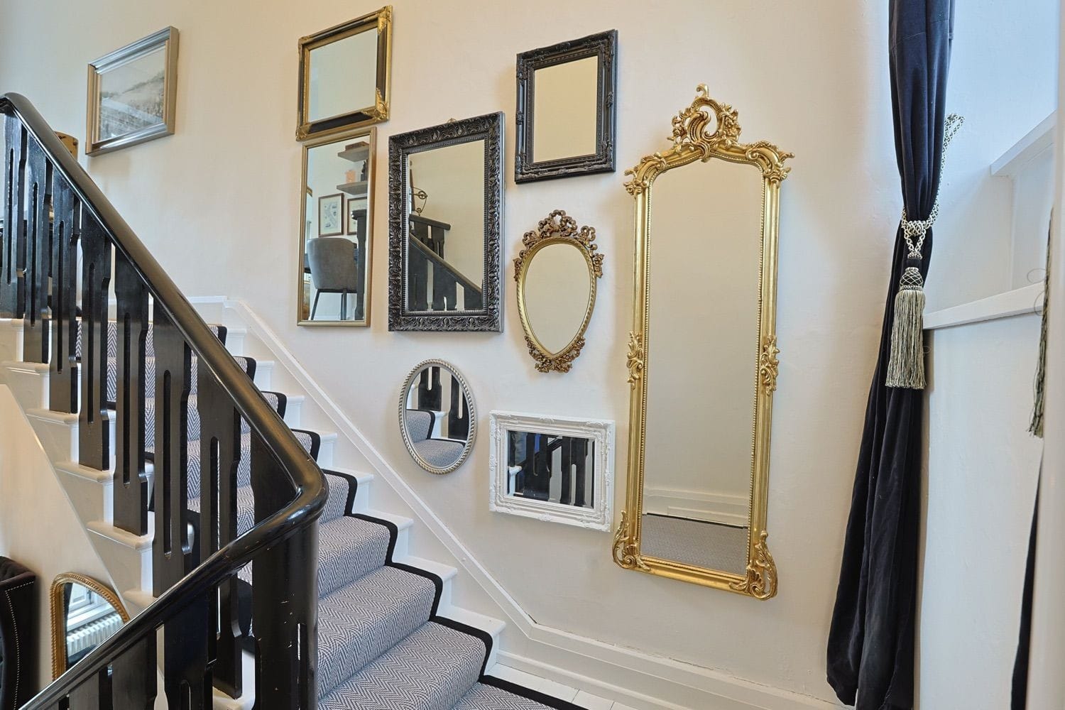 A beautifl mix of framed mirrors hanging up the staircase makes a perfect statement