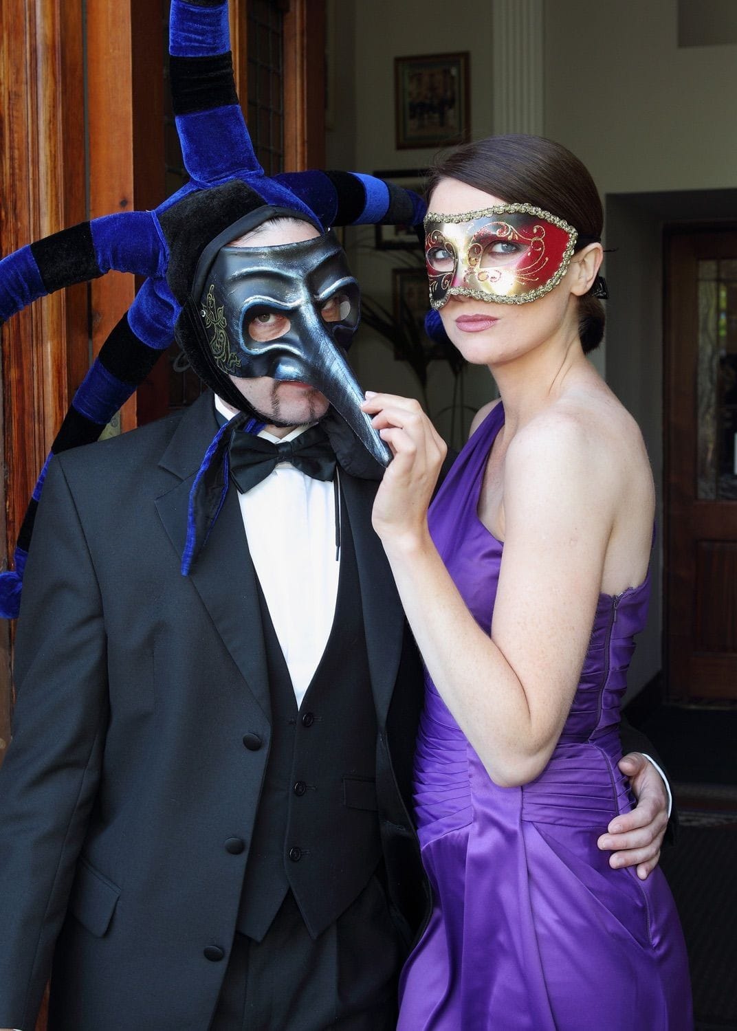 Jennifer Zamparelli dressed in a stunning purple dress poses with a character at the Clayton Hotel to launch the Freemason of Ireland Masquerade Ball