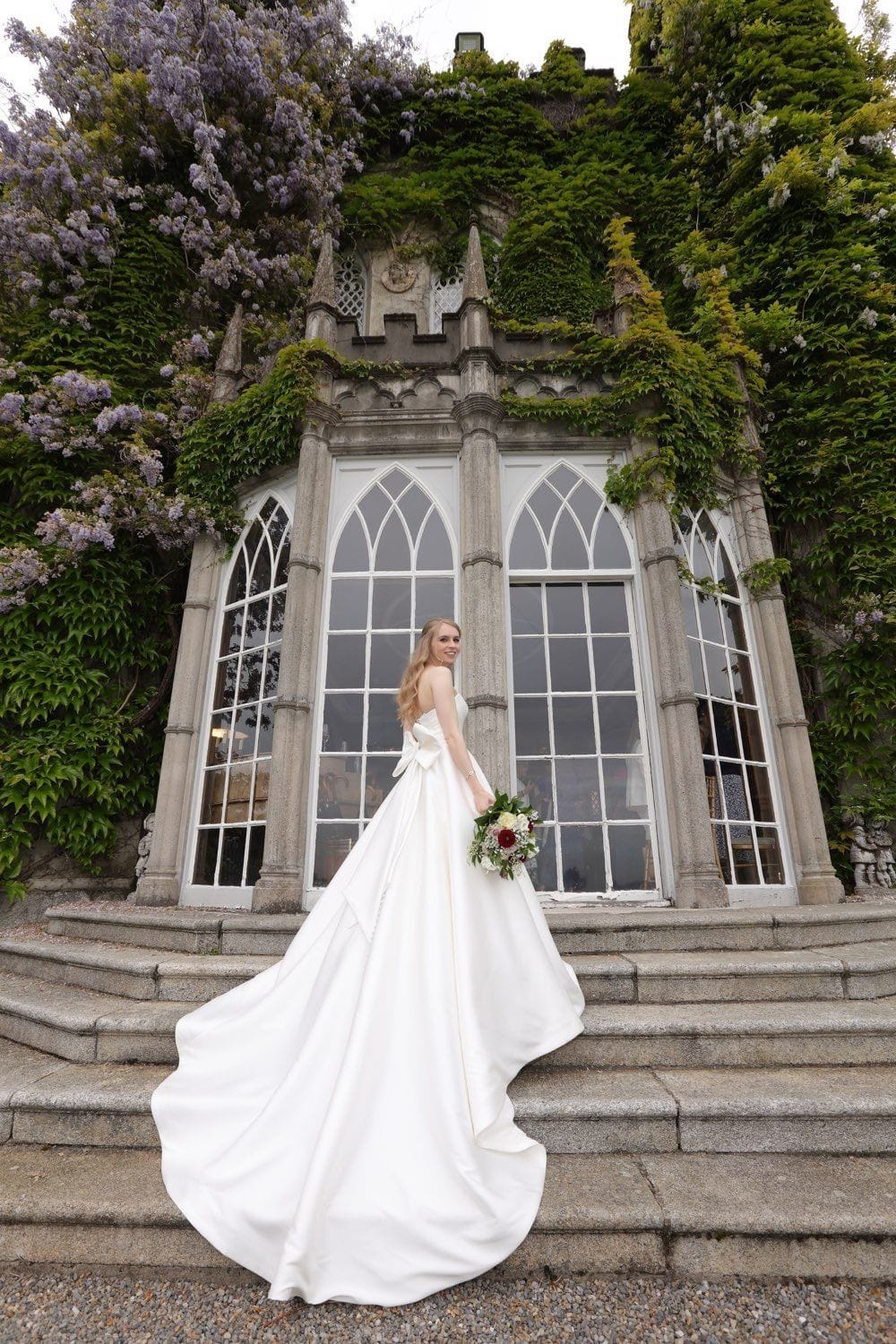 The lovely bride standing showing off the detail of her dress, on the steps up to the library of Luttrelstown Castle