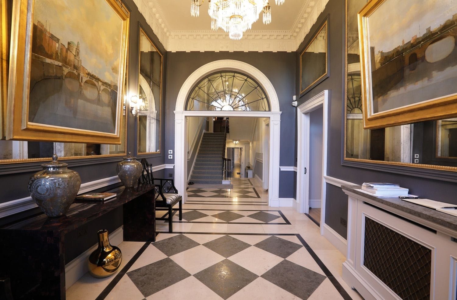 A view from the front door down through a beautiful arch with a glass fan to the stairs