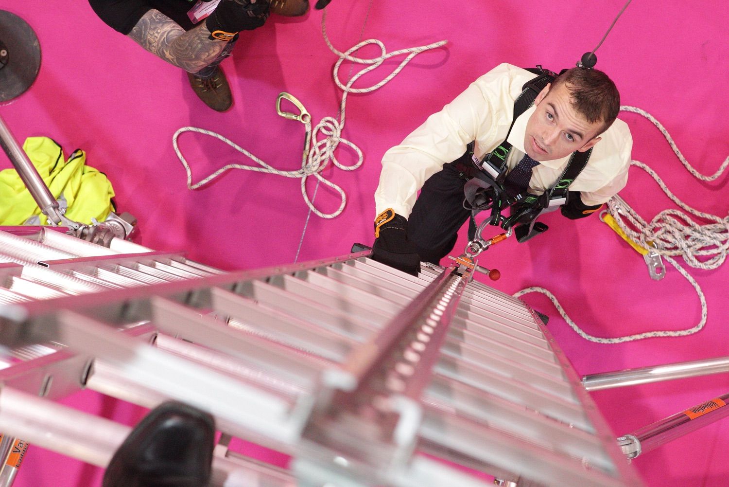 An attendee at a trade show starts to climb a ladder with the aid of a harness at a trade show in the RDS main Hall, Dublin