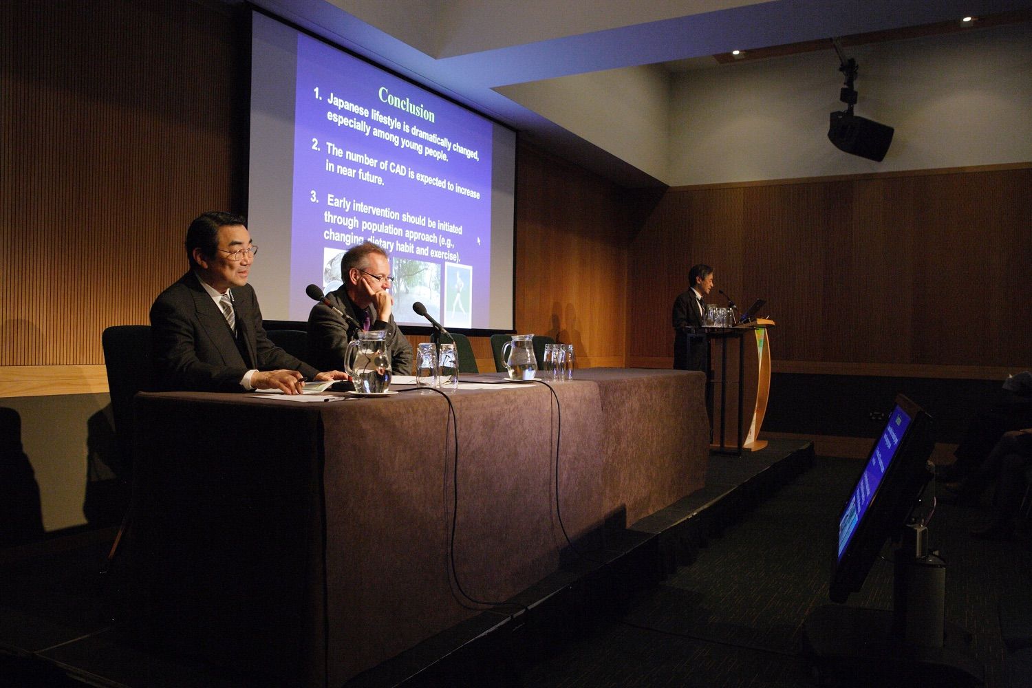 Two speakers listening to a third speaker addressing the audience ata  conference in the Convention Centre Dublin