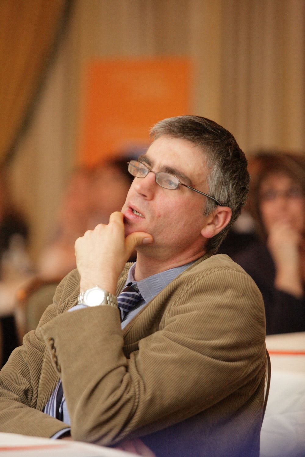 A delegate rubs his chin thoughtfully during a conference session