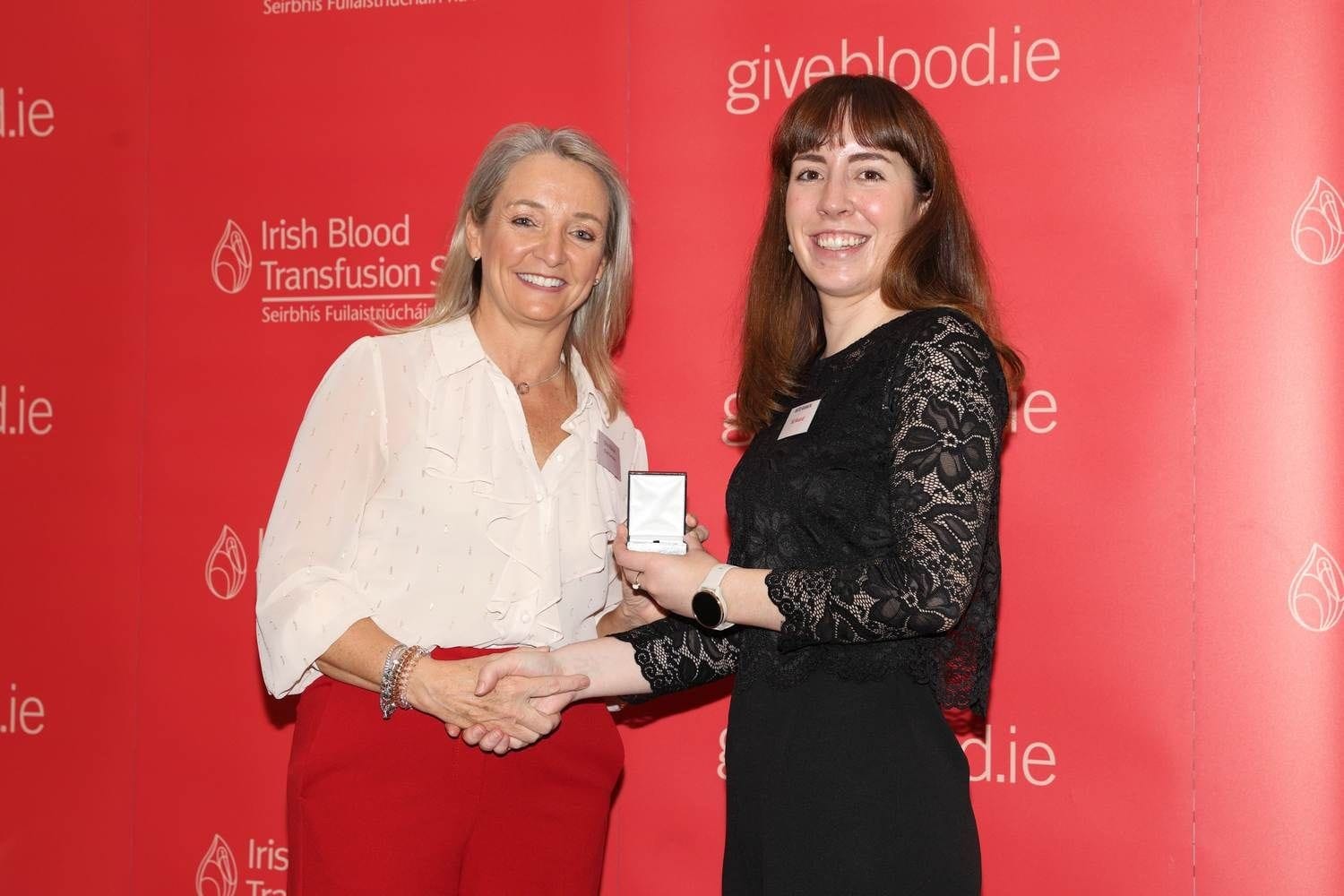 A donor accepting her fifty  time donation award of a golden drop of blood pin.