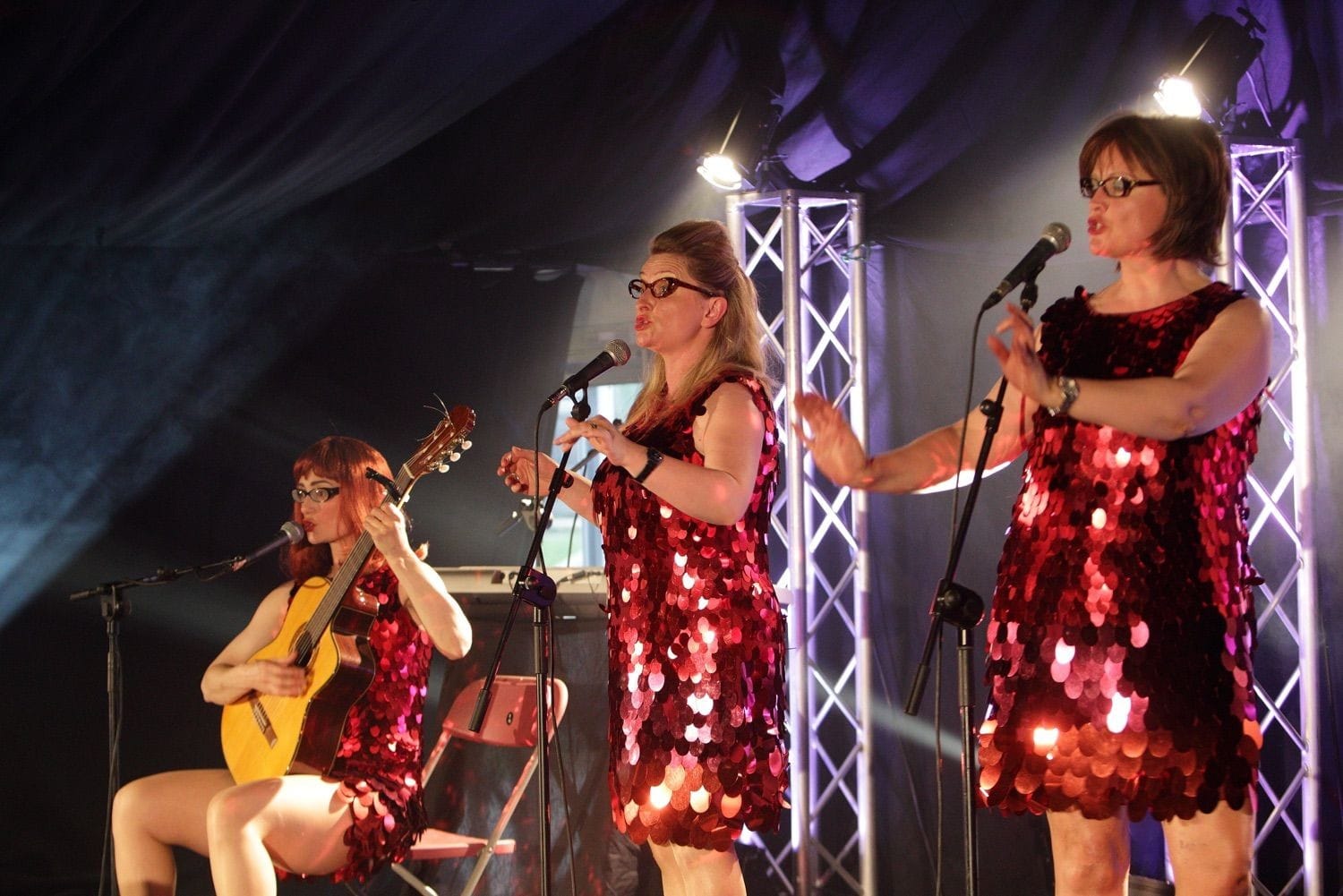 The Three Nualas onstage in red sequined dresses at the Vodafone Comedy Festival, held in the Iveagh Gardens, Dublin, Ireland